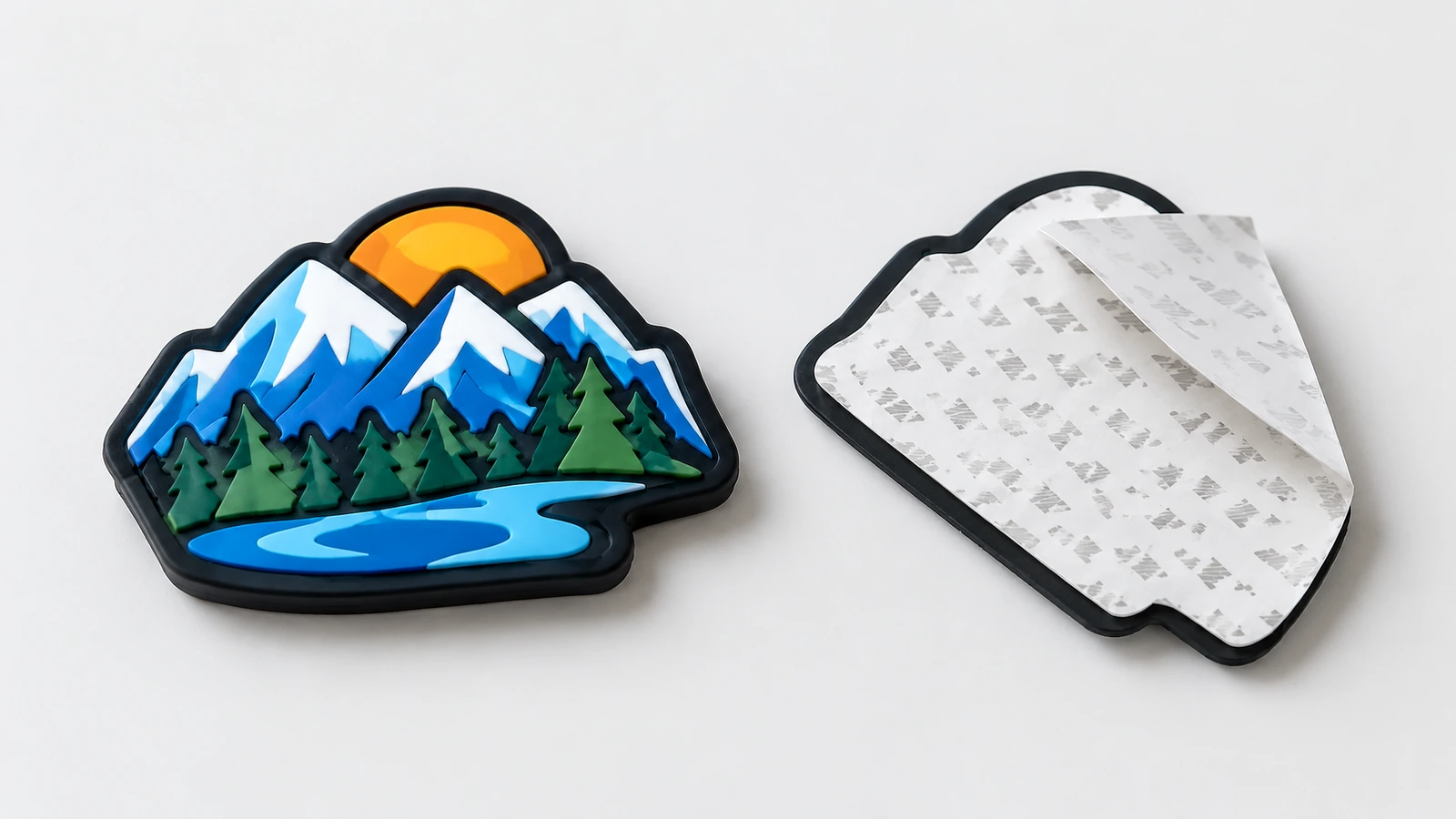 볼록한 라벨 앞면과 접착 뒷면 산 디자인 소프트 PVC 라벨이 접착 뒷면 및 일부 벗겨낸 이형지와 나란히 앞면이 위로 보이도록 놓인 모습